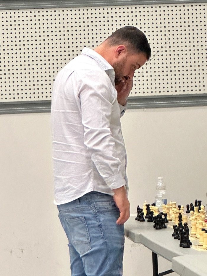 El gran maestro Pepe Cuenca pensando su jugada junto a una fila de tableros durante las partidas simultáneas